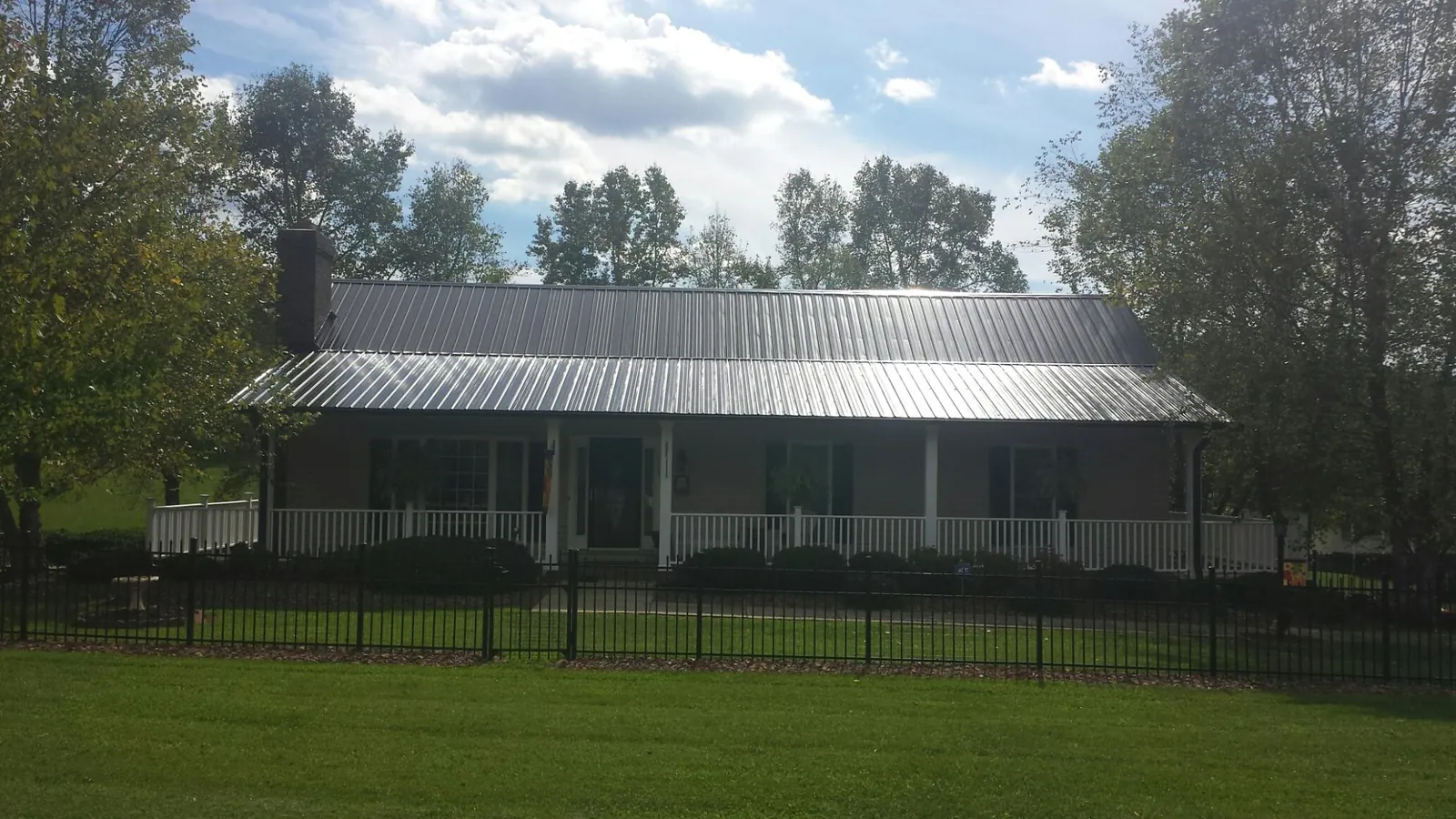 Gray metal roof on a brick ranch with a full width front porch — Gutter Guard Installation work by our crew in Dillon