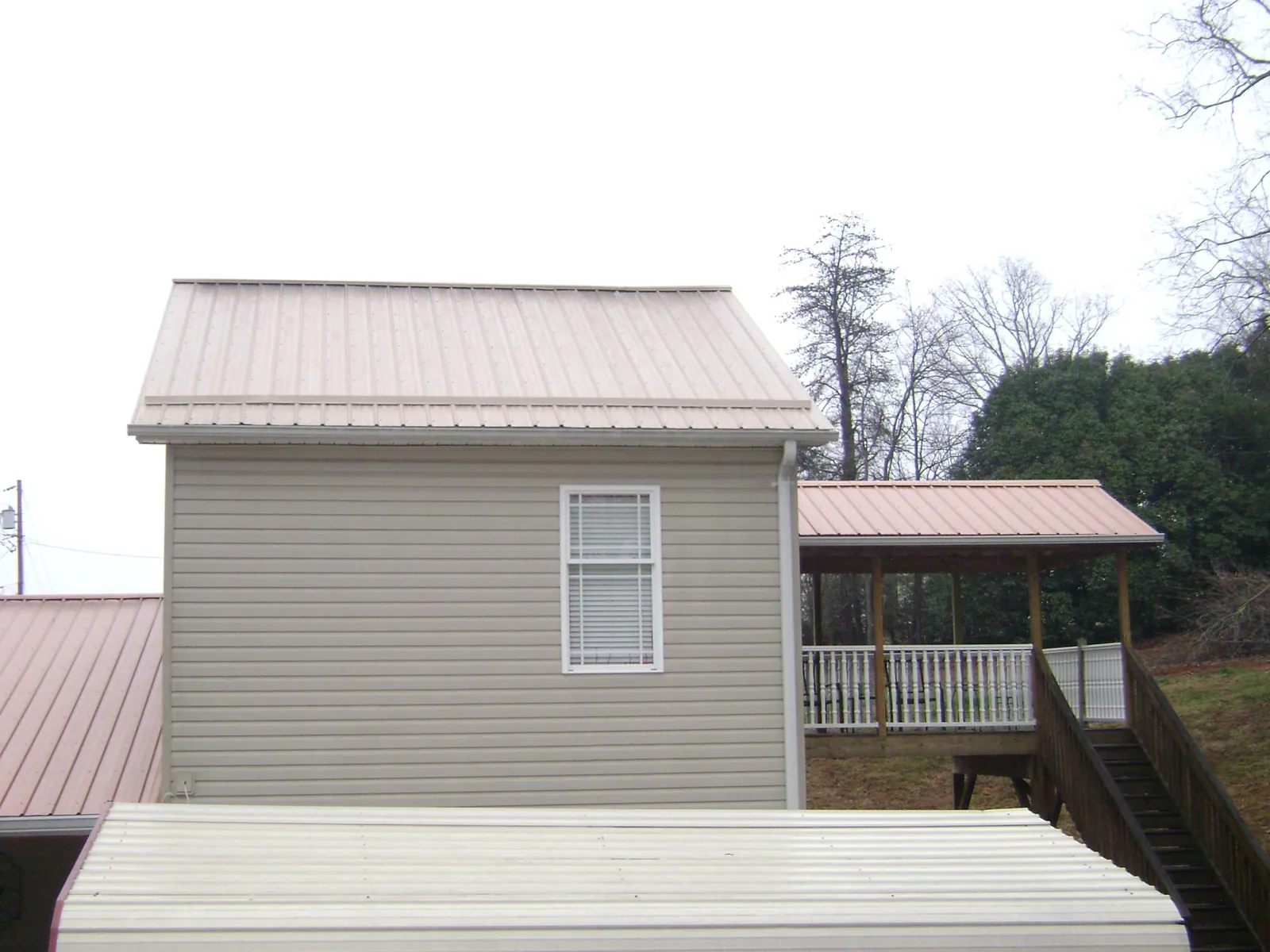 Tan metal roofs on a two story addition and attached porch, from a Roof Replacement job in Dillon