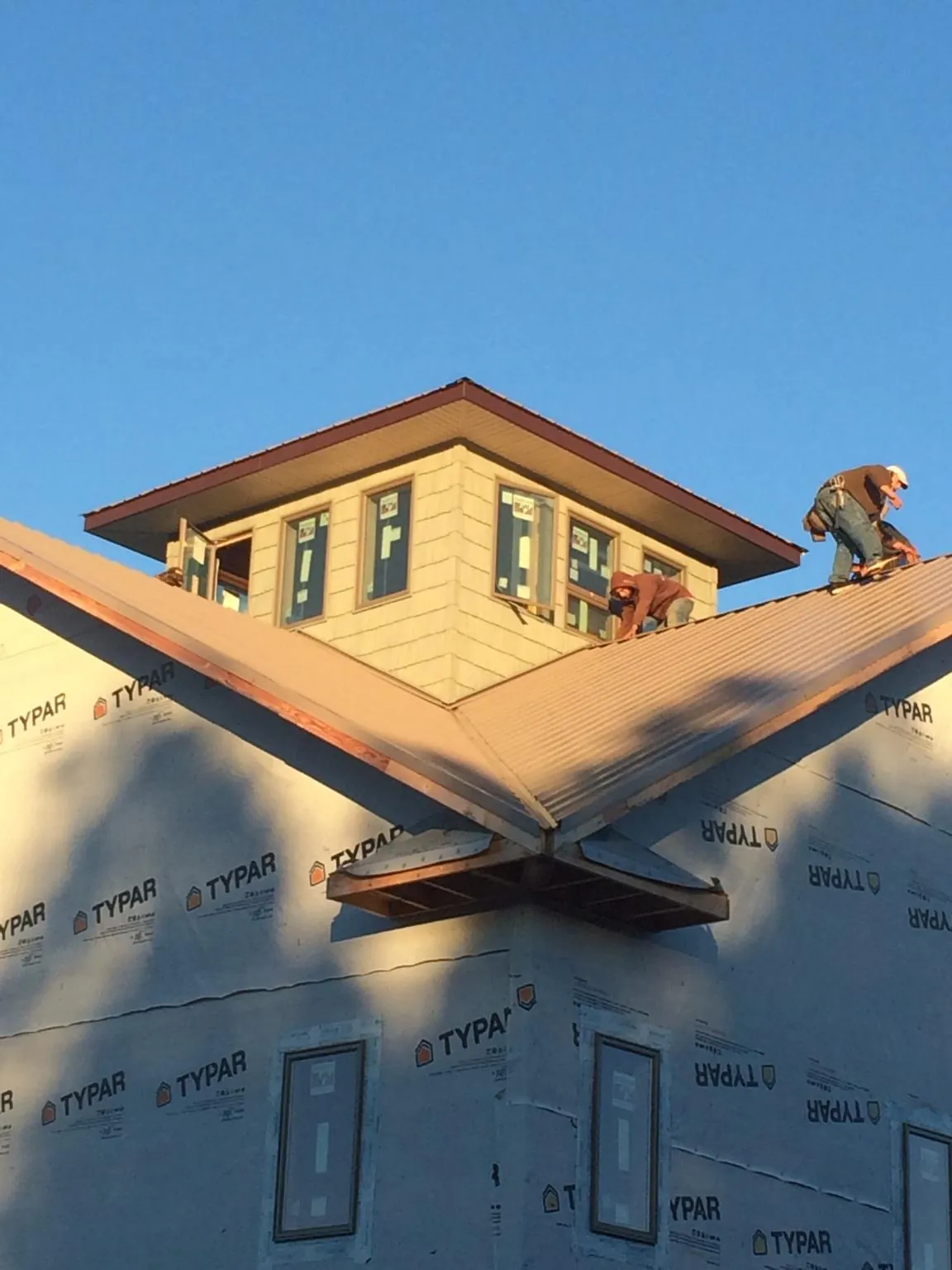 Roofers working around a rooftop cupola on a new metal roof at sunset — Roof Waterproofing in Dillon by Roofing Brothers